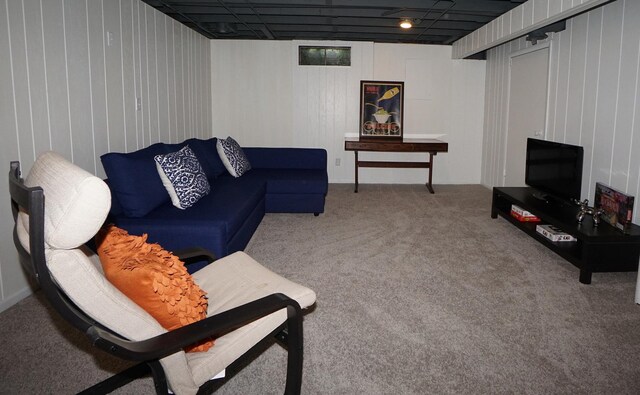 carpeted living room featuring wood walls