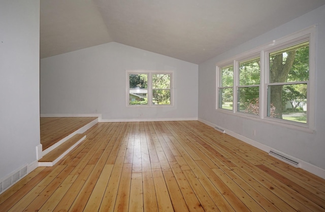 additional living space with light hardwood / wood-style floors and lofted ceiling