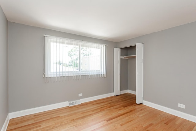 unfurnished bedroom featuring baseboards, a closet, visible vents, and light wood-type flooring