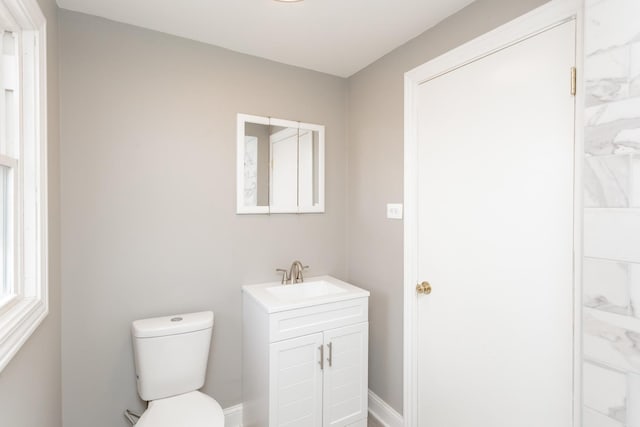half bathroom featuring baseboards, vanity, and toilet