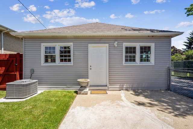 back of house with central AC, a patio area, and a lawn