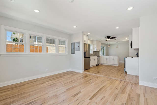 unfurnished living room with ceiling fan, electric panel, and light hardwood / wood-style flooring