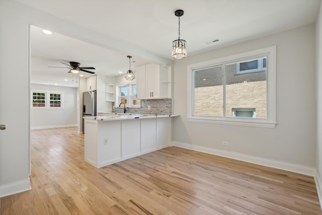 kitchen featuring light wood-type flooring, white cabinetry, kitchen peninsula, and a wealth of natural light