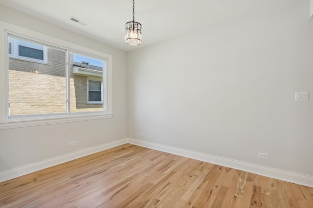 unfurnished room with a chandelier and light wood-type flooring