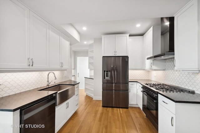 kitchen featuring light hardwood / wood-style floors, black appliances, sink, white cabinets, and wall chimney exhaust hood