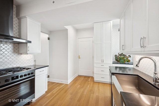 kitchen with white cabinetry, wall chimney exhaust hood, stainless steel range with gas stovetop, and sink