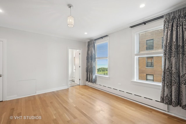 spare room featuring hardwood / wood-style floors, crown molding, and a baseboard radiator