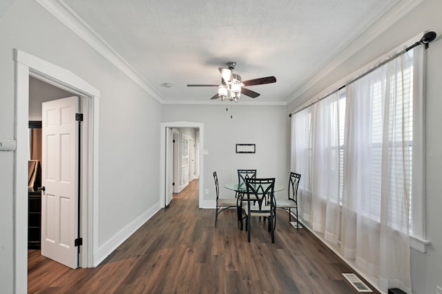 dining room with crown molding, dark wood-type flooring, a textured ceiling, and ceiling fan