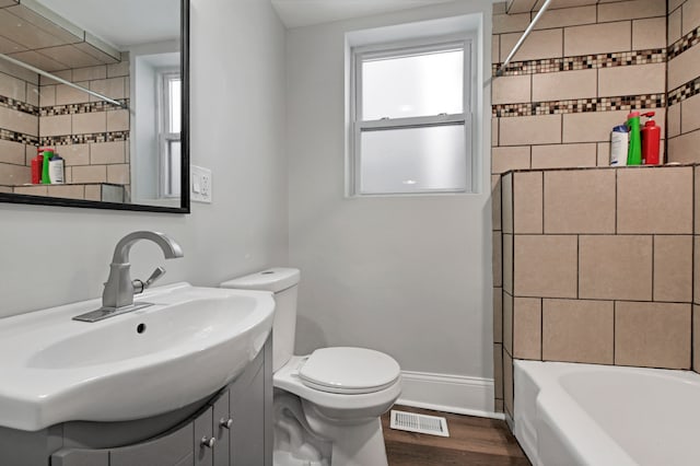 full bathroom with vanity, tiled shower / bath combo, wood-type flooring, and toilet