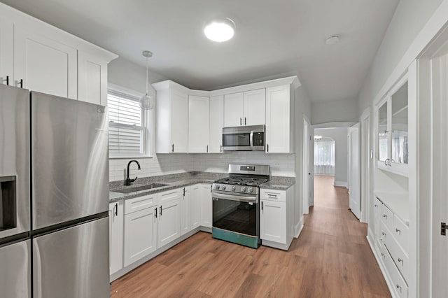 kitchen with white cabinetry, light hardwood / wood-style floors, appliances with stainless steel finishes, and sink