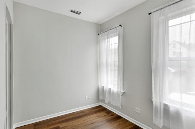 spare room with dark wood-type flooring and plenty of natural light