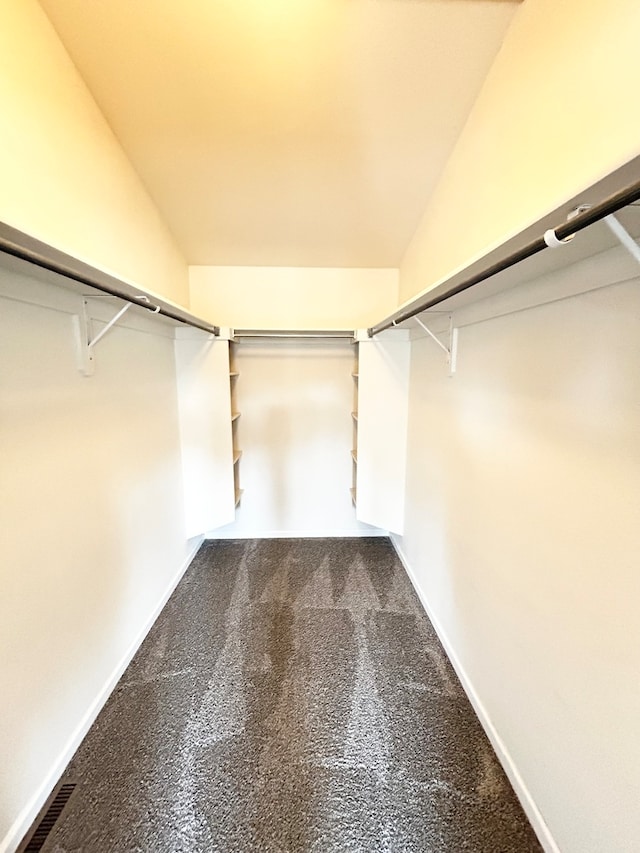 spacious closet with carpet floors, lofted ceiling, and visible vents