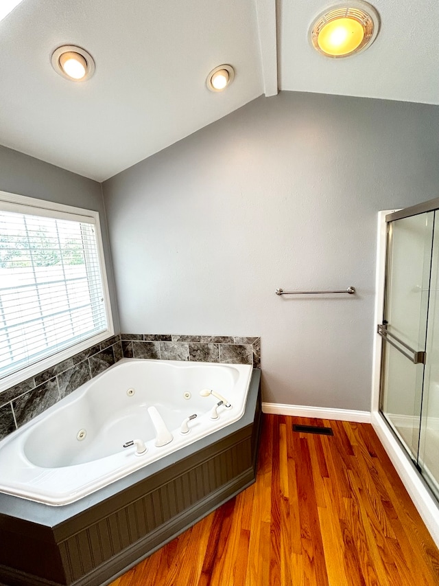 full bathroom featuring a shower with shower door, wood finished floors, baseboards, vaulted ceiling, and a tub with jets