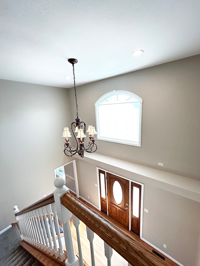 foyer entrance with baseboards, stairway, visible vents, and a notable chandelier