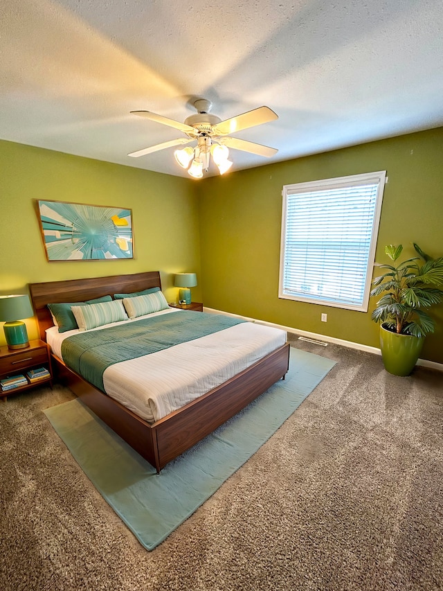 carpeted bedroom with a textured ceiling, a ceiling fan, and baseboards