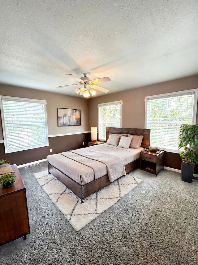 carpeted bedroom featuring a textured ceiling, ceiling fan, and baseboards