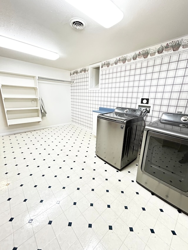 washroom with laundry area, washing machine and dryer, visible vents, and light floors