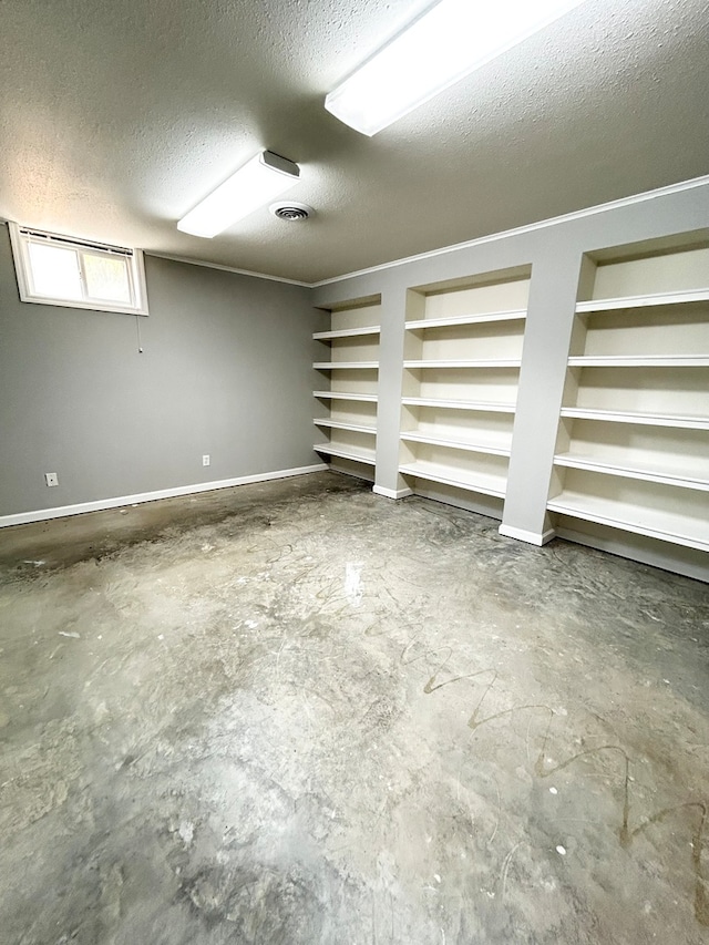 below grade area with built in features, visible vents, a textured ceiling, and baseboards