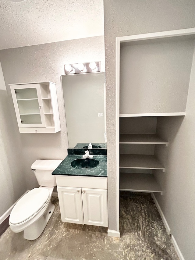 half bathroom with toilet, baseboards, and vanity