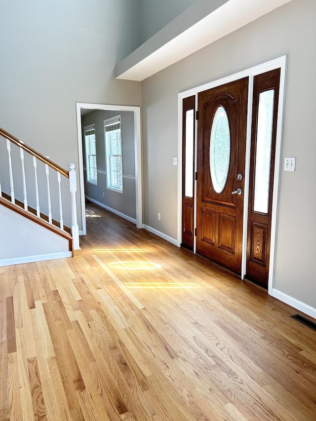 foyer with baseboards, stairway, and light wood-style floors