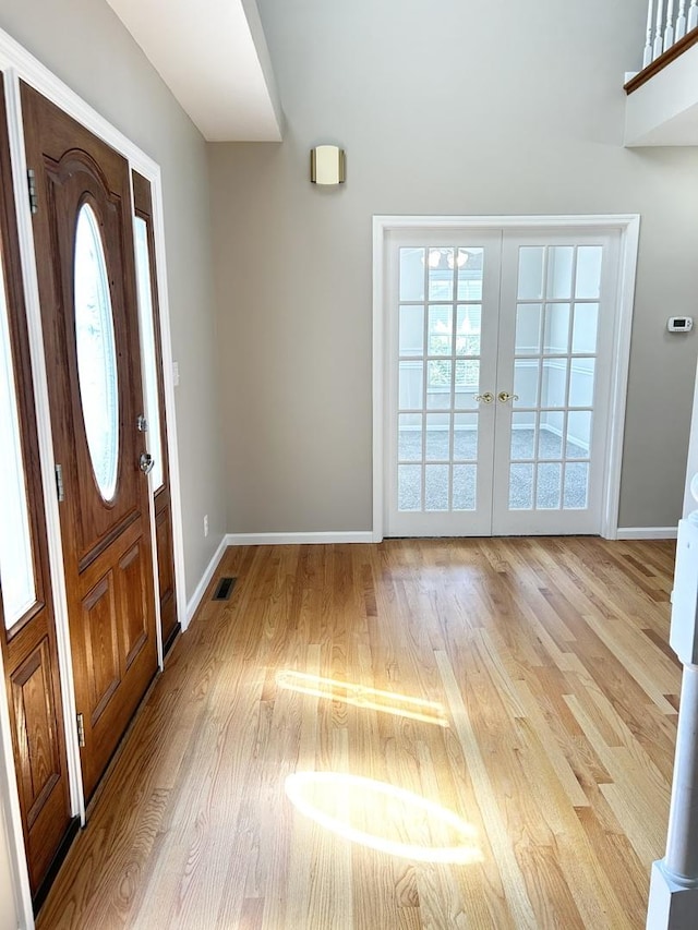 foyer entrance with french doors, light wood-type flooring, visible vents, and baseboards