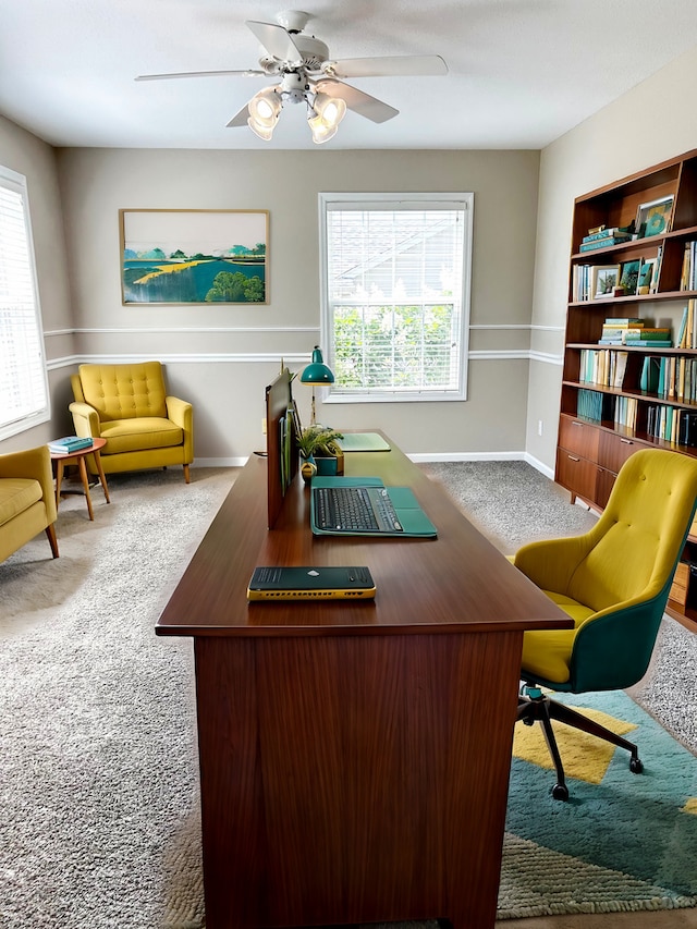 carpeted home office featuring a ceiling fan, a wealth of natural light, and baseboards