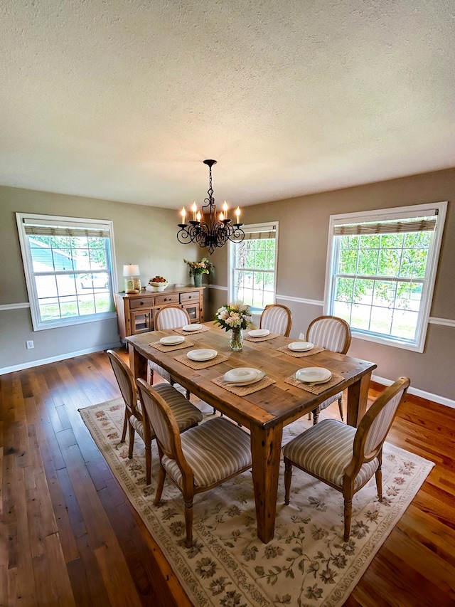 dining room with an inviting chandelier, a textured ceiling, baseboards, and dark wood-style flooring