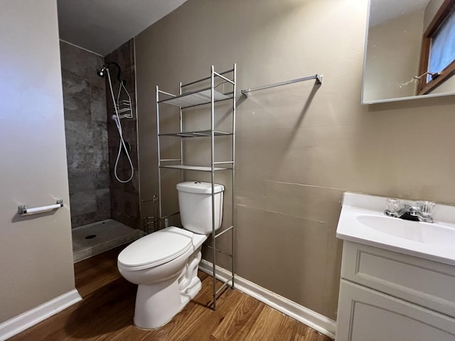 bathroom featuring tiled shower, vanity, wood-type flooring, and toilet