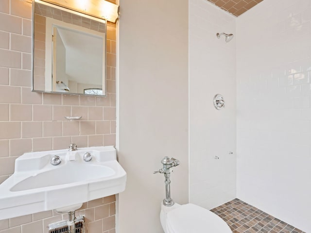 bathroom featuring sink, tiled shower, decorative backsplash, toilet, and tile walls