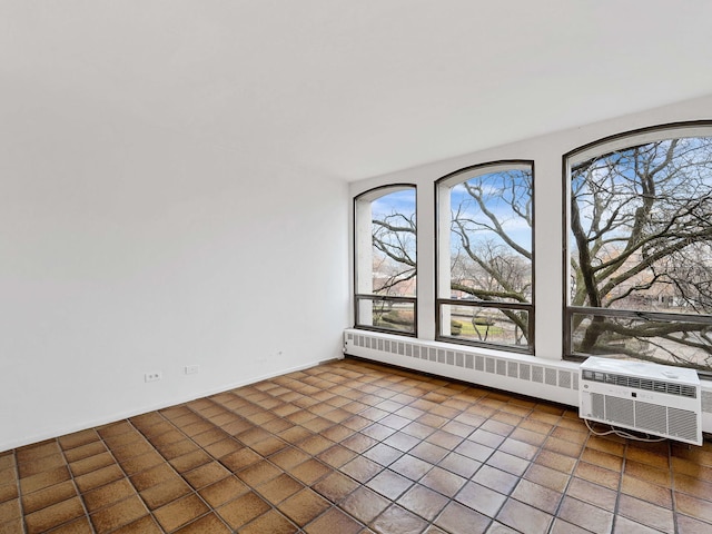 unfurnished room with dark tile patterned flooring, radiator, and a wall mounted AC