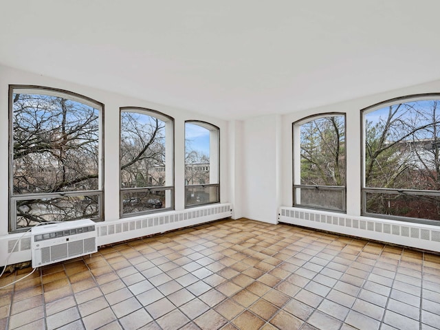 unfurnished sunroom featuring a wall mounted air conditioner, a healthy amount of sunlight, and a baseboard heating unit