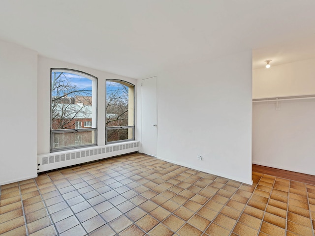 spare room with radiator heating unit and light tile patterned floors