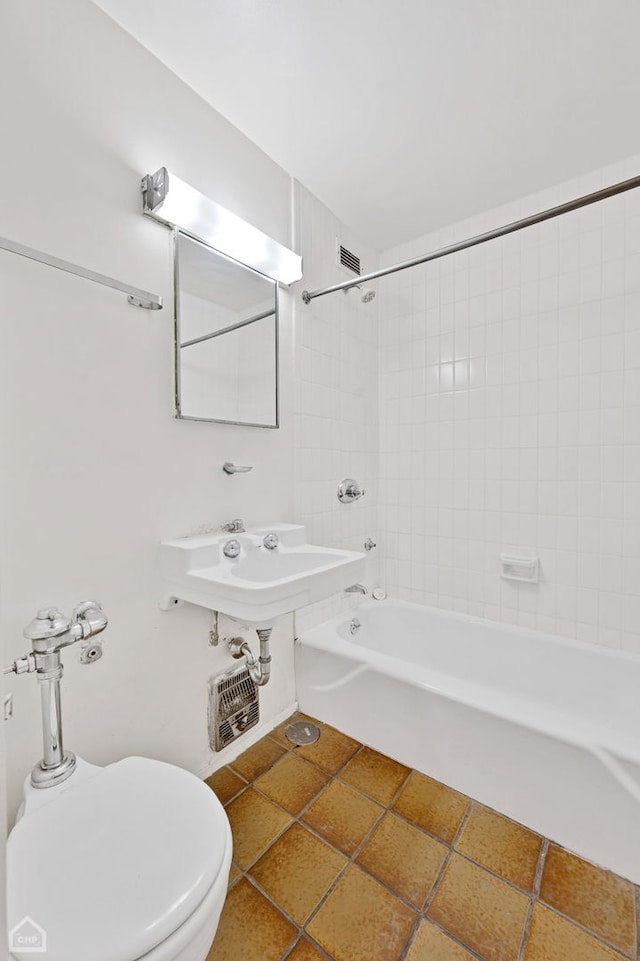 bathroom featuring toilet and tiled shower / bath