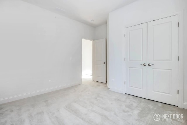 unfurnished bedroom featuring light colored carpet and a closet