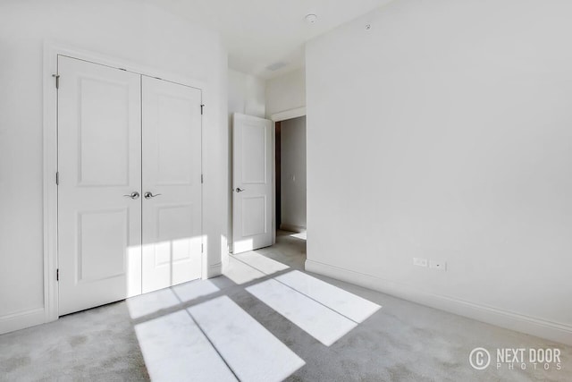 unfurnished bedroom featuring a closet and light colored carpet