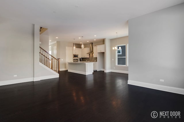 unfurnished living room featuring dark hardwood / wood-style floors, a notable chandelier, and sink