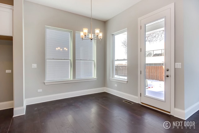 unfurnished dining area with dark wood-type flooring and a notable chandelier