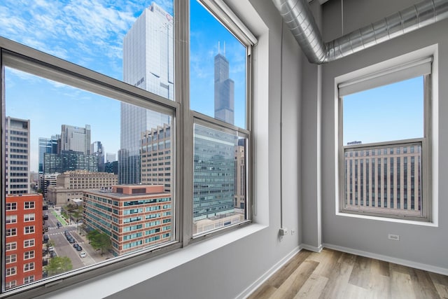 unfurnished room with a view of city, wood finished floors, and baseboards