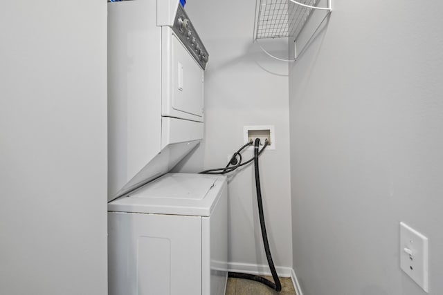 laundry area featuring laundry area, baseboards, and stacked washer / drying machine