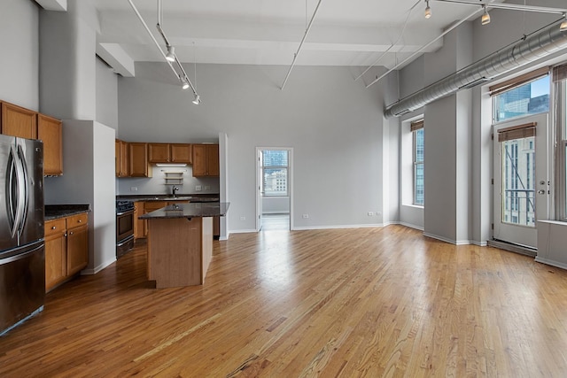 kitchen featuring light wood-style floors, freestanding refrigerator, brown cabinets, and a sink