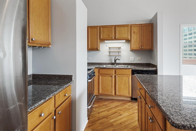 kitchen with appliances with stainless steel finishes, dark stone counters, and a sink