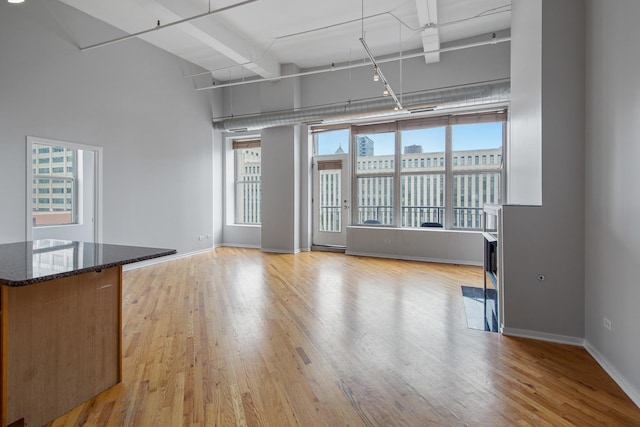 interior space featuring light wood-type flooring, rail lighting, and baseboards