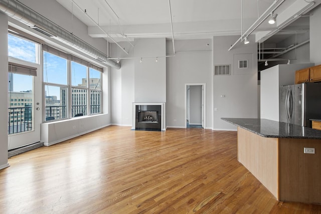 kitchen featuring a towering ceiling, light wood-style floors, visible vents, and freestanding refrigerator