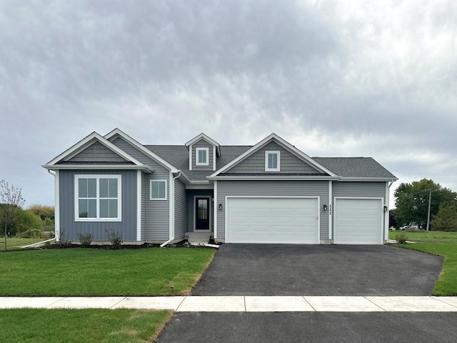 view of front facade with roof with shingles, an attached garage, board and batten siding, driveway, and a front lawn