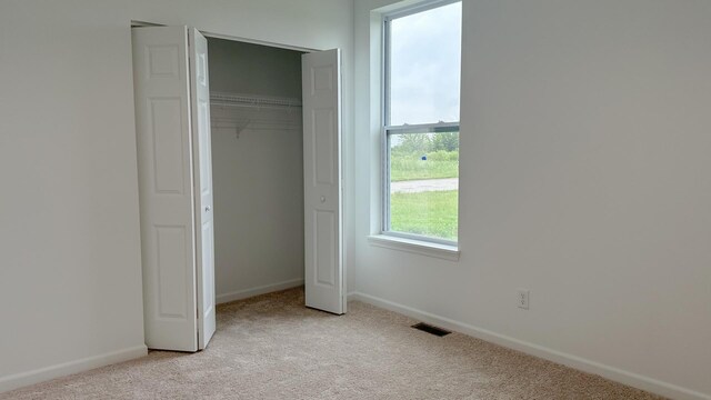 unfurnished bedroom featuring light carpet and a closet