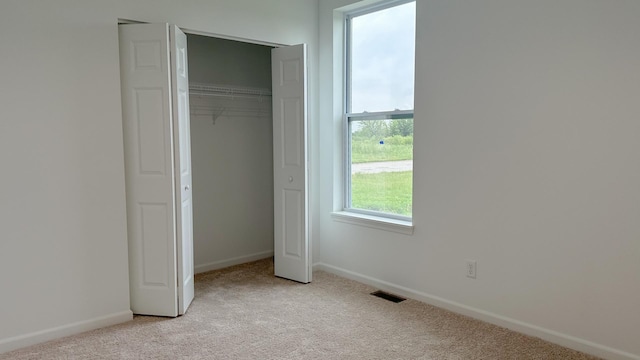 unfurnished bedroom with light carpet, visible vents, and baseboards