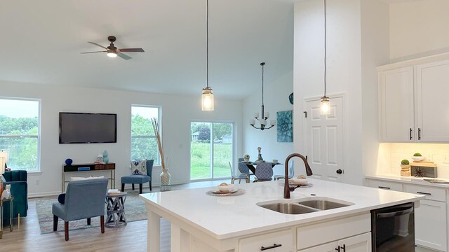 kitchen with decorative light fixtures, white cabinets, black dishwasher, a center island with sink, and light hardwood / wood-style floors