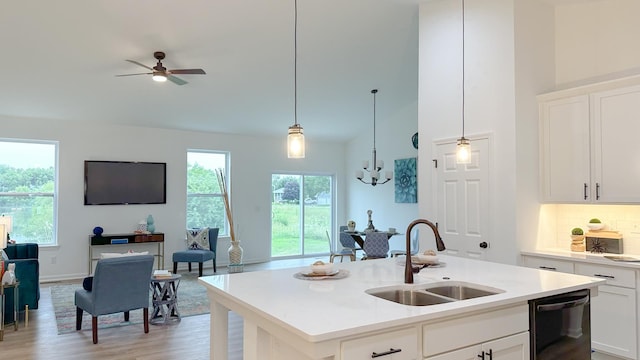 kitchen featuring black dishwasher, open floor plan, a kitchen island with sink, white cabinetry, and a sink