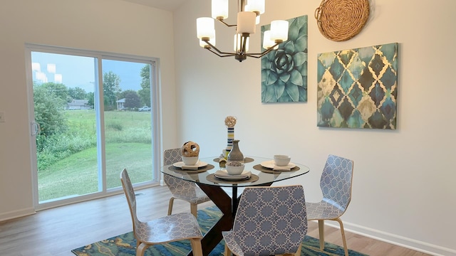 dining area featuring baseboards, wood finished floors, and an inviting chandelier