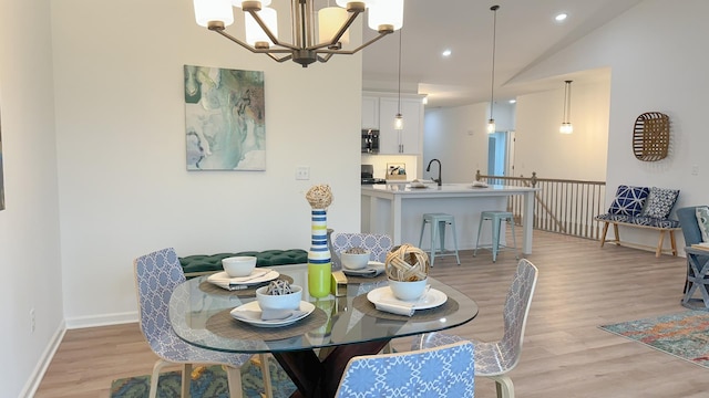 dining area with a notable chandelier, recessed lighting, baseboards, vaulted ceiling, and light wood-type flooring